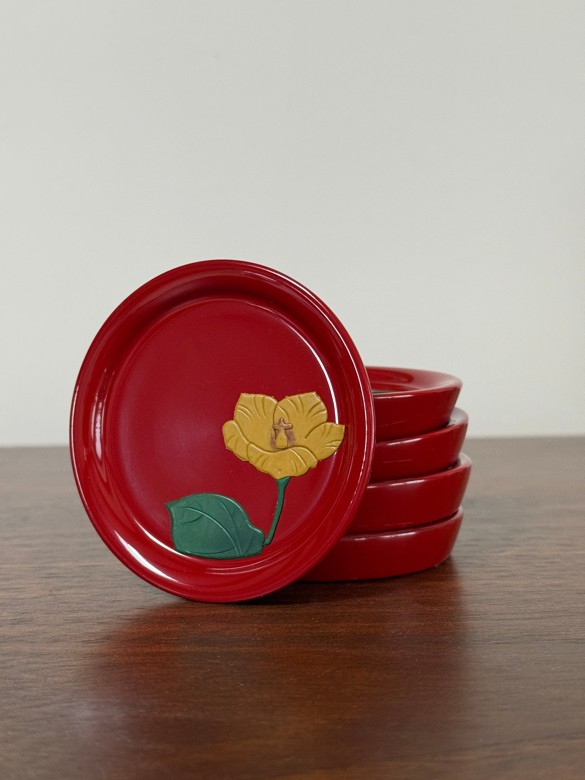 Red  plates with yellow flower design on a wooden surface