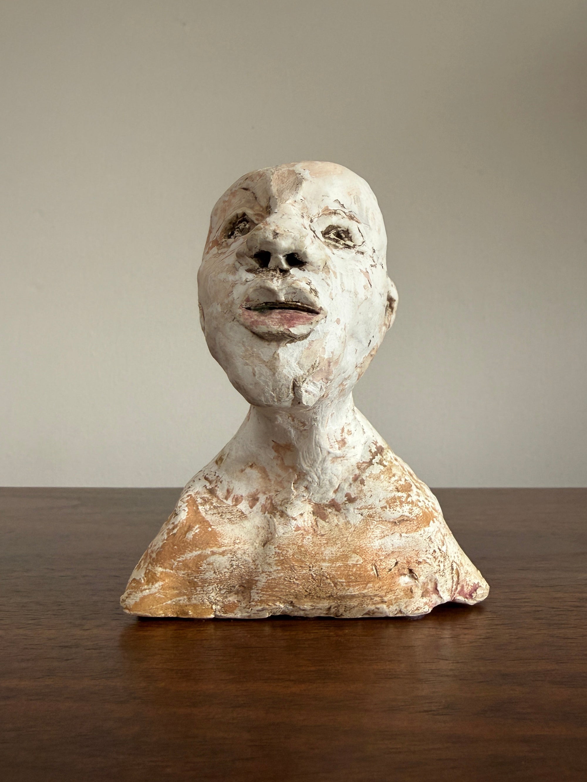 Ancient sculpture head on a plain background