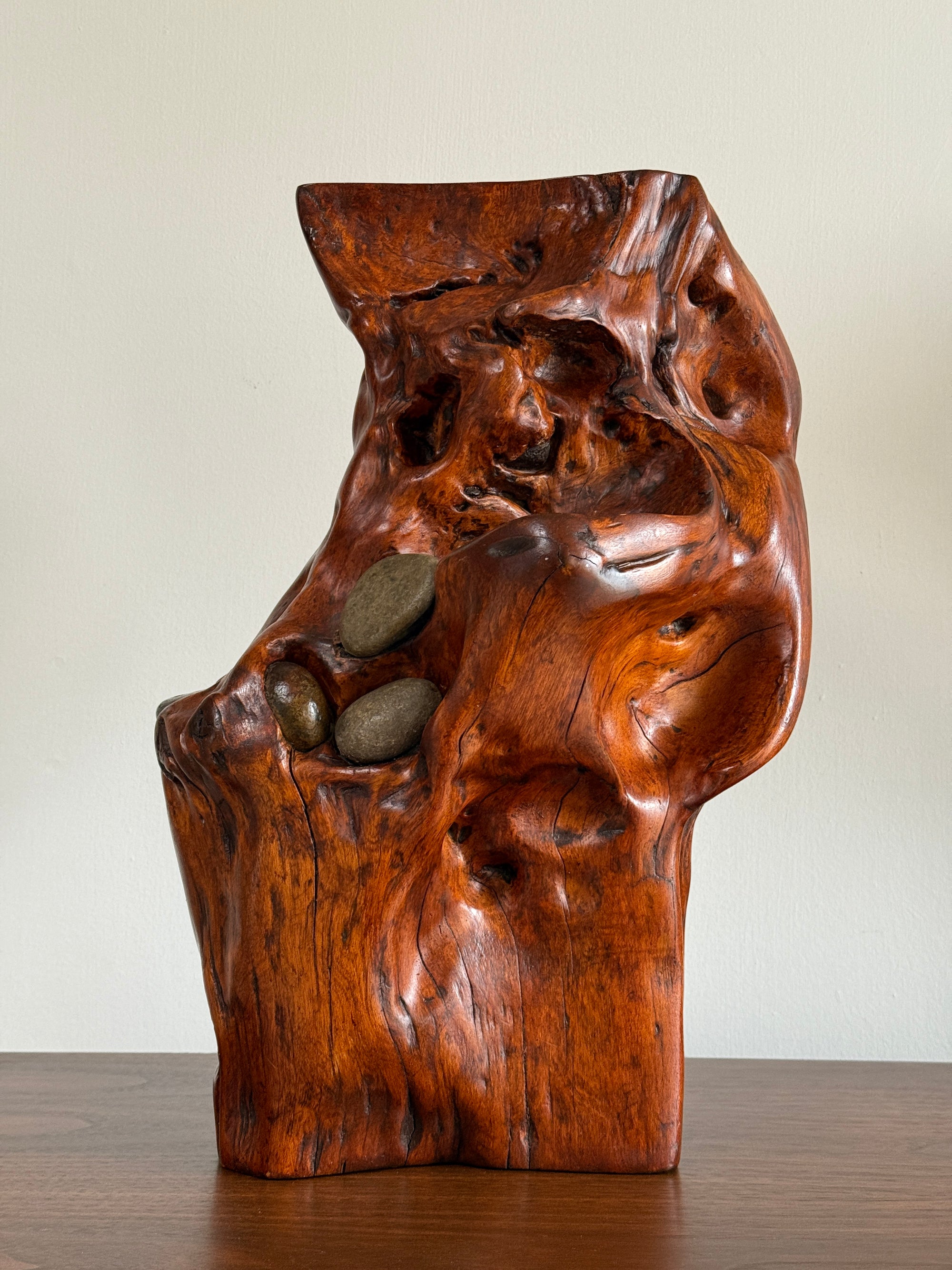 Wooden sculpture with embedded stones on a plain background