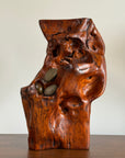 Wooden sculpture with embedded stones on a plain background